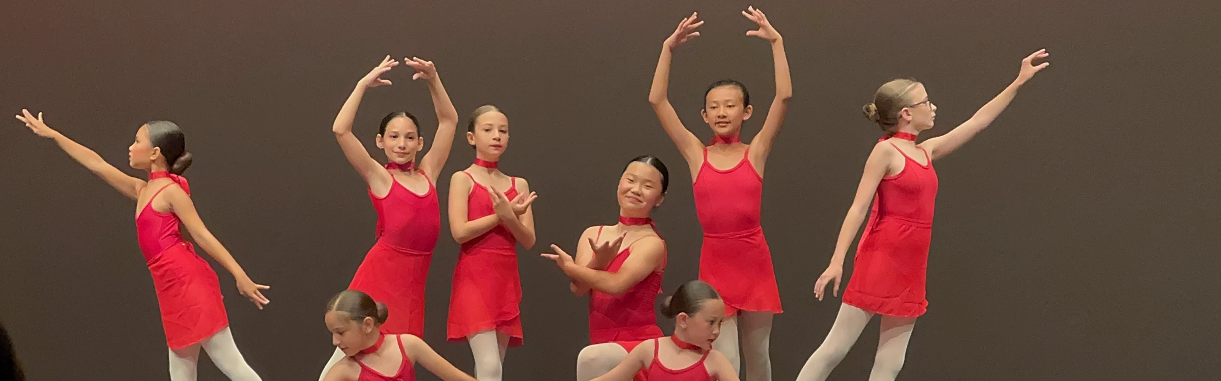 Serendipity dancers performing together on stage in red costumes